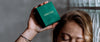 Loretana model holding green branded jewelry box against glass block wall, Baltic silver atelier story from Kaunas. Hallmarked piece.