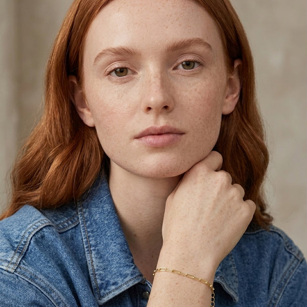 Woman with copper hair wearing the 14K gold-plated paperclip chain bracelet with extender chain and small tag