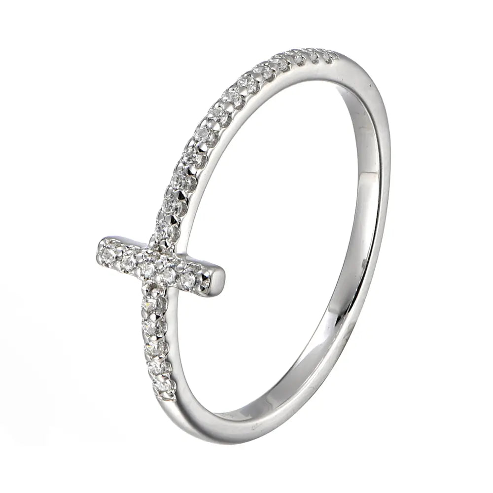 Rokas modelis valkā sudraba krusta cirkonija gredzenu no 925 sterlinga sudraba ar rodiēšanas pārklājumu, plāns krusta motīvs, kas gludi atrodas pret pirkstu mīkstā dienasgaismā. Zīmogs Loretana izstrādājumam, roku apdare Kaunā.